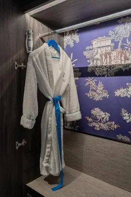 a robe hanging on a wall with a blue ribbon at Madi Paidi Bangkok, Autograph Collection in Bangkok