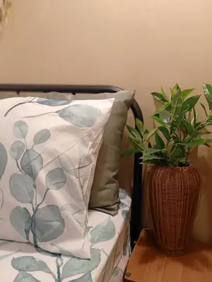 a pillow and a plant in a vase on a table at Be Local BNB in Bangkok