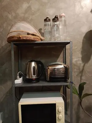 a shelf with a tea kettle and a toaster on top of a microwave at Be Local BNB in Bangkok