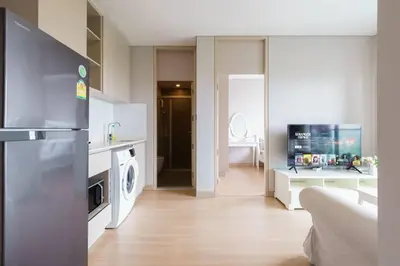 a kitchen and living room with a refrigerator and a stove at Lumpini Suite Phetchaburi Siam Square Nana in Ban Non Phatthana