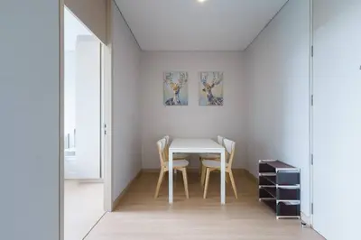 a white dining room with a table and chairs at Lumpini Suite Phetchaburi Siam Square Nana in Ban Non Phatthana