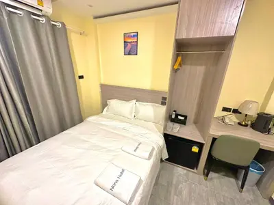a small room with a bed and a desk and a computer at Nona Hotel, Bangkok in Makkasan