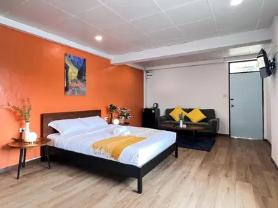 a bedroom with a bed with an orange wall at Jaruchok Apartment in Bangkok