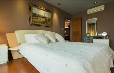 a bedroom with a large white bed with a painting on the wall at Sukhumvit Boutique Suite : Soi 13/ 10min. from BTS Nana station in Bangkok
