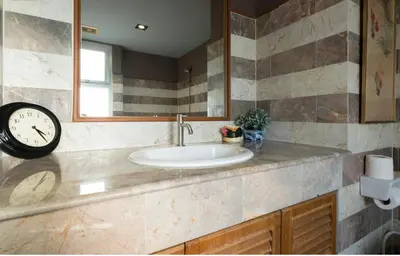 a bathroom with a sink and a clock on a counter at Sukhumvit Boutique Suite : Soi 13/ 10min. from BTS Nana station in Bangkok