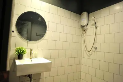 a white tiled bathroom with a sink and a mirror at STAY-DIUM House Huamark in Ban Bang Toei (1)