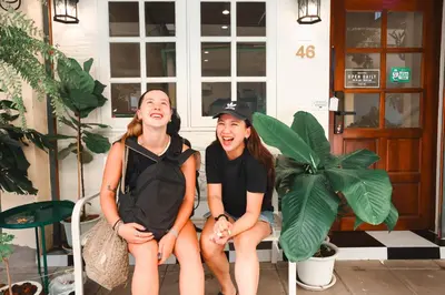 two young women sitting on a porch with their mouths at Noir Cafe And Hostel Chinatown Bangkok in Chinatown