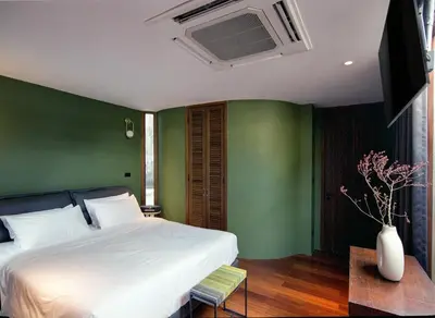 a bedroom with a white bed and a green wall at Na Tanao 1969 in Bangkok