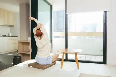 a woman doing a yoga pose in a living room at LiveZen Bangkok Sukhumvit in Khlong Toei
