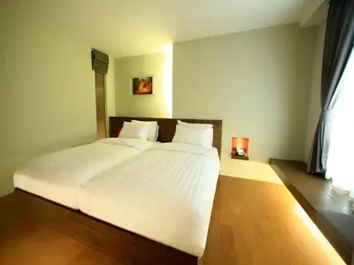 a bedroom with a large bed with white sheets at Silom One in Bangkok