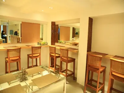 a kitchen with a bar with wooden chairs and a glass table at Silom One in Bangkok