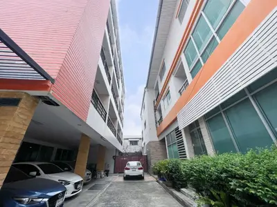 a car parked in a parking lot between two buildings at Tongyang House Serviced Apartment in Bangkok