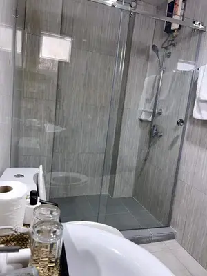 a bathroom with a shower and a toilet and a sink at Tongyang House Serviced Apartment in Bangkok