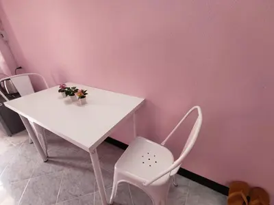 a white table and chair in a room with a pink wall at Worakarn Apartment 3 in Bangkok