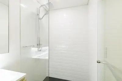 a white bathroom with a shower and a sink at Loft Pool Superior Suite Near jodd Night Market 500mbps Wi-Fi Twin in Bangkok