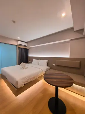 a bedroom with a large bed and a table at Lucky Elephant Hotel in Ban Bang Toei (1)