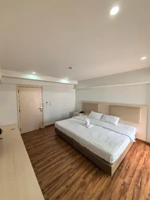 a bedroom with a large white bed and wooden floors at Lucky Elephant Hotel in Ban Bang Toei (1)