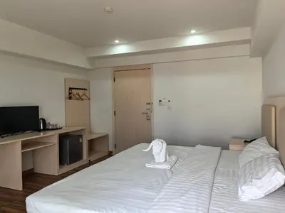 a bedroom with a large white bed and a flat screen tv at Lucky Elephant Hotel in Ban Bang Toei (1)
