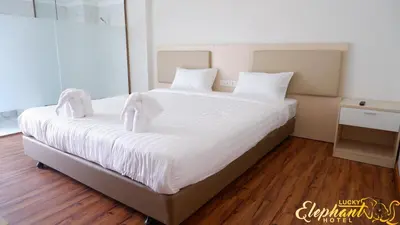 a large bed with white sheets and white pillows at Lucky Elephant Hotel in Ban Bang Toei (1)