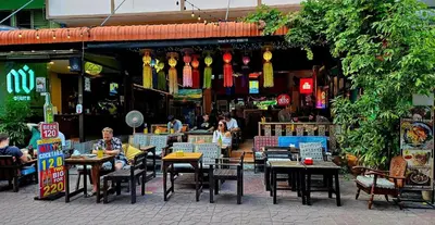 a group of people sitting at tables in a restaurant at Merry V Guesthouse in Bangkok