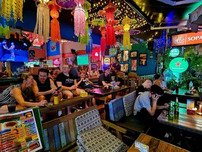 a group of people sitting at a bar at Merry V Guesthouse in Bangkok