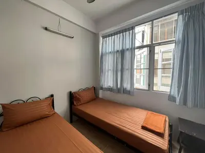 a bedroom with two beds and a window at Merry V Guesthouse in Bangkok