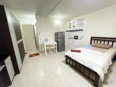 a bedroom with a bed and a table and a kitchen at Popular The best muangthongthani \u65e5\u5e38\u623f\u95f4\u516c\u5bd3 in Ban Bang Phang