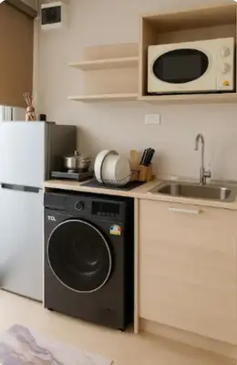 a kitchen with a washing machine and a microwave at Elio Del Ray condo feel resort in Bangkok