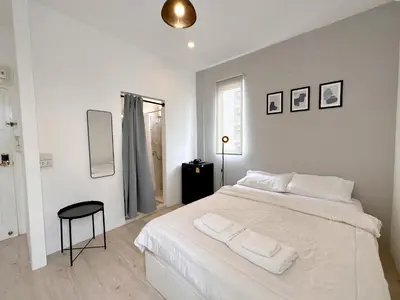 a white bedroom with a white bed and a stool at Na Ekkamai Residence in Bangkok