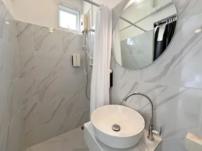 a white bathroom with a sink and a mirror at Na Ekkamai Residence in Bangkok
