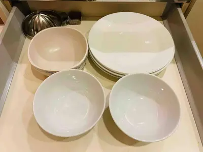 four white bowls and plates on a counter at Luxury 1BR 300m BTS PhromPhong, Empo, EmQ, EmSphere, Rooftop Pool, Gym, Fast 500mbps wifi in Bangkok