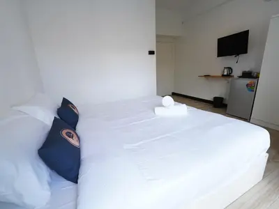 a bedroom with a white bed with pillows and a television at RoomQuest IT Square Don Mueang Airport in Bangkok