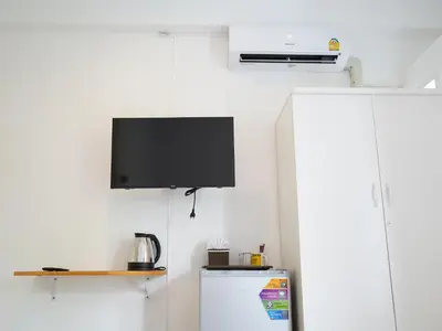 a kitchen with a tv on the wall and a refrigerator at RoomQuest IT Square Don Mueang Airport in Bangkok
