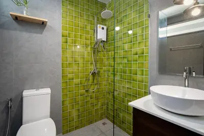 a green tiled bathroom with a sink and a shower at Homie Non - โฮมมี่ นนท์ in Ban Bang Khwang