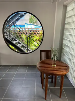 a circular window in a room with a wooden table at Homie Non - โฮมมี่ นนท์ in Ban Bang Khwang