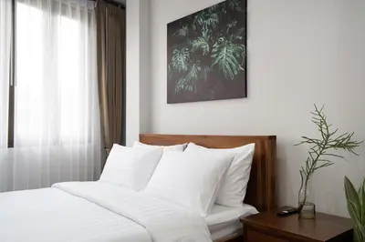 a bedroom with a bed with white sheets and a window at Homie Non - โฮมมี่ นนท์ in Ban Bang Khwang