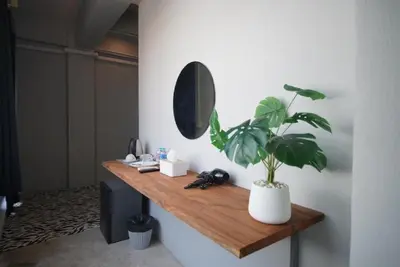 a mirror and a potted plant on a wooden shelf at The Character Yaowarat เดอะคาแลตเตอร์ เยาวราช in Khlong San