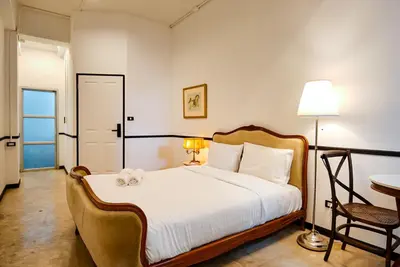 a bedroom with a bed and a chair and a table at The Character Yaowarat เดอะคาแลตเตอร์ เยาวราช in Khlong San