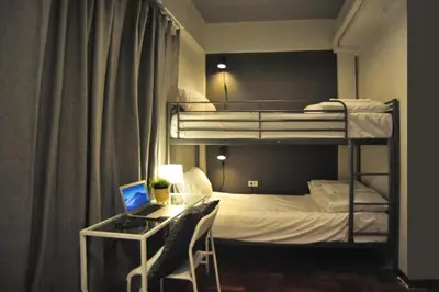 a bedroom with bunk beds with a desk and a laptop at Tuk Tuk House 250m from MRT Sirikit in Bangkok