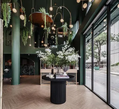 a table in a room with green walls and windows at Cher Hostel Bangkok in Bangkok