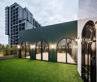 a building with a green lawn in front of a building at Cher Hostel Bangkok in Bangkok