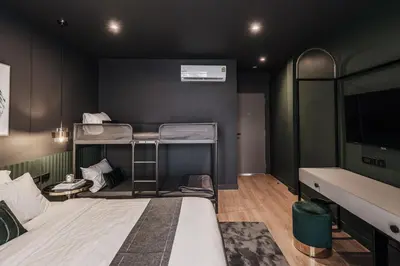 a room with two bunk beds and a flat screen tv at Cher Hostel Bangkok in Bangkok