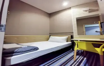 a bedroom with two beds and a desk and a tv at Capital O 75451 Podstel Hostel Bangkok in Bangkok