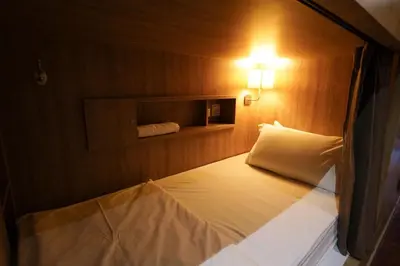 a small room with a bed with a light on it at The poshtel Bangkok By Benya BTS Phayathai in Bangkok