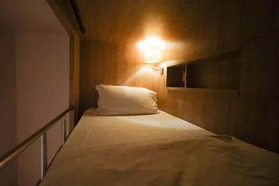 a bedroom with a bed with a light on it at The poshtel Bangkok By Benya BTS Phayathai in Bangkok