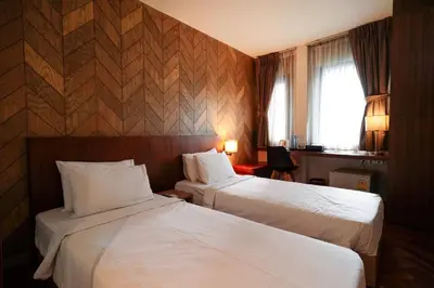 a hotel room with two beds and a window at The poshtel Bangkok By Benya BTS Phayathai in Bangkok