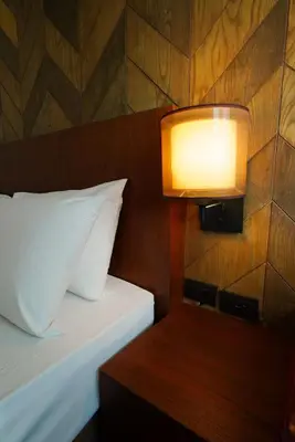 a bedroom with a bed with a light on the wall at The poshtel Bangkok By Benya BTS Phayathai in Bangkok