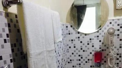 a bathroom with a white towel and a mirror at Sukhumvit 20 Guest House in Bangkok