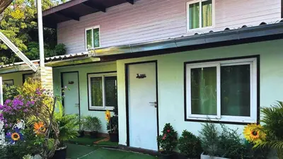 a house with a white door and some flowers at Magic Garden Residence Bangkok in Bangkok