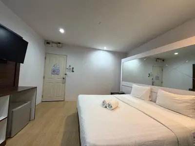 a bedroom with a large white bed with a television at Bed By Cruise Hotel At Samakkhi-Tivanont in Nonthaburi